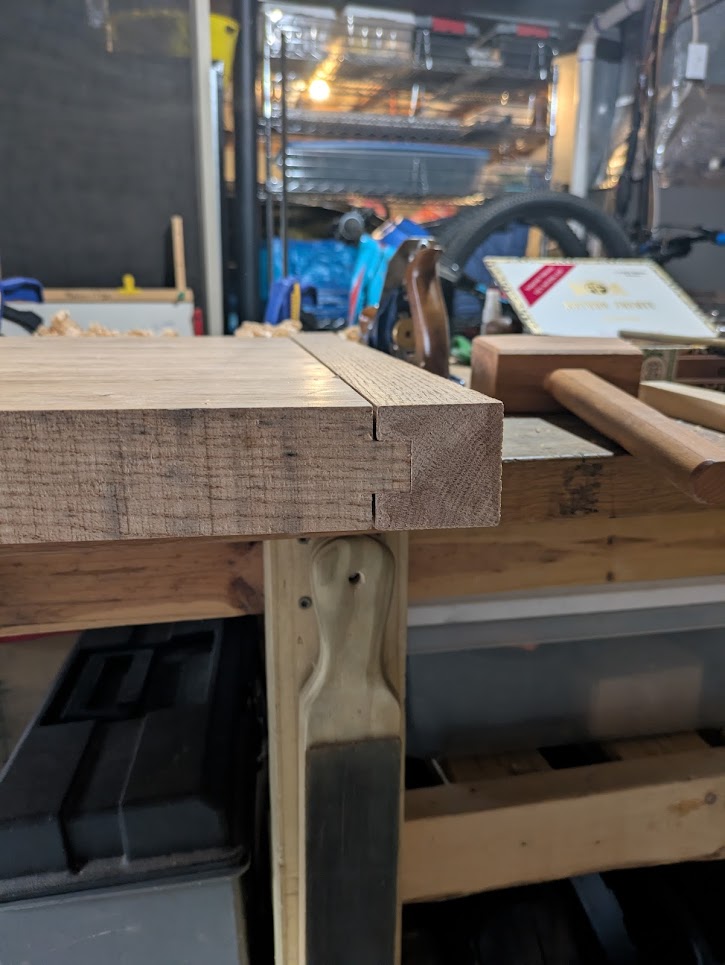 Looking at the side of the table top and seeing a small gap between the shoulders of the tongues and the breadboard end.